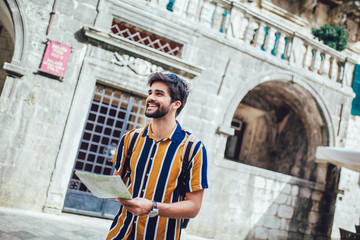 Fototapeta na wymiar Handsome bearded tourist with backpack is making travel across city.