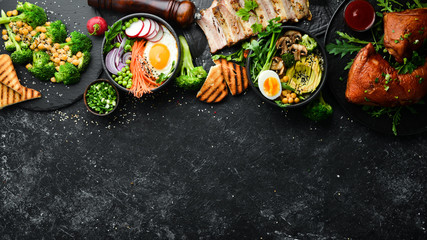 Food: pasta, pork ribs, avocado, Buddha bowl and beet salad on a black stone background. Top view....