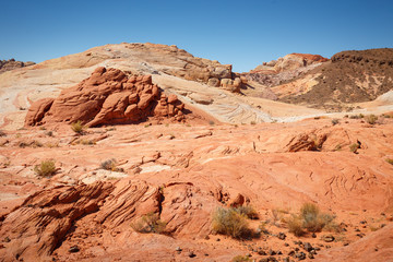 Mountains surrounding Fire wave during wonderful sunny day with blue sky, in Valley of Fire State Park, Nevada, USA