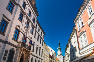 Fototapeta na wymiar Aged Slovak houses Michalska street and Saint Michael Gate under blue sky, Old Town of Bratislava city, Slovakia
