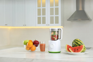 Blender and smoothie ingredients on table in kitchen