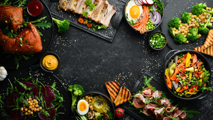 Food: pasta, pork ribs, avocado, Buddha bowl and beet salad on a black stone background. Top view. Free space for text.