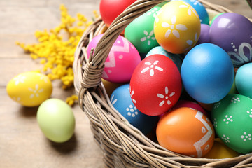 Basket with colorful Easter eggs on table, closeup