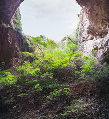 Devetashka cave interior, near Lovech town, Bulgaria. Panorama of entrance tunnel with hole on top and deep green grass