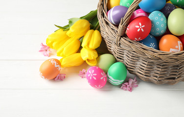 Fototapeta na wymiar Colorful Easter eggs and flowers on white wooden background. Space for text