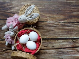 festive Easter layout of three eggs in a straw basket with a rabbit on a colored background