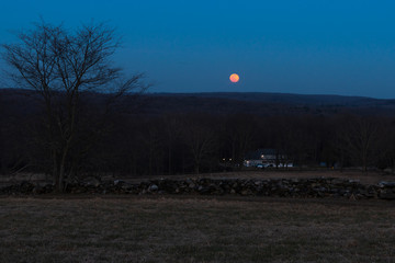 The rise of the Super Moon over a farm