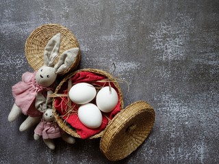 festive Easter layout of three eggs in a straw basket with a rabbit on a colored background