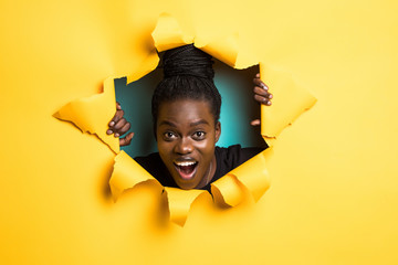Smile afro american woman posing from yellow paper hole