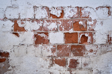 Background. An old red brick wall with peeled white paint and peeled plaster.