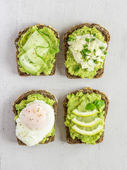 Variety of sandwiches for breakfast, snack, appetizer - avocado puree, poached egg, cucumber, lemon, cheese, whole grain bread sandwiches. On a light background, banner. Vegetarian food. 