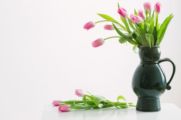 Fototapeta na wymiar pink tulips on green jug on white background