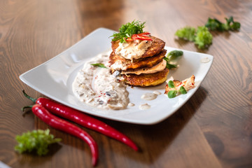 Potato pancekes in a white plate on wooden table