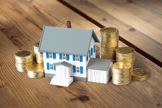 Model Of A Mini House With Coins On A Table