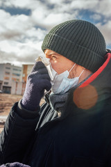 man in a hat, jacket and gloves blows his nose. face shield against viruses