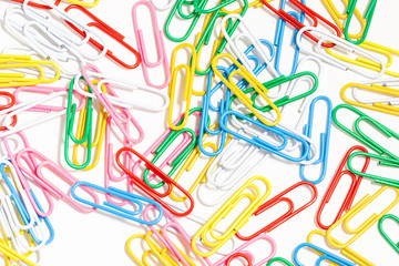 Multicolored paper clips on a white background. Different color wire plugs for documents. Office supplies abstract concept.