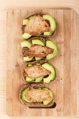 Sliced avocado and fried sliced chicken breast fillet on cereal bread.