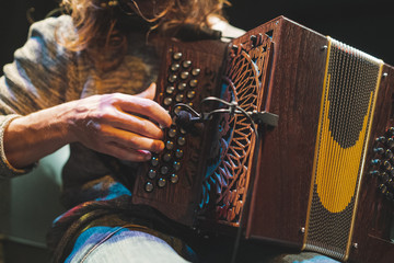 Accordionist playing accordion on stage closeup. Folk music festival picture. Focus on the hands playing the instrument. - obrazy, fototapety, plakaty