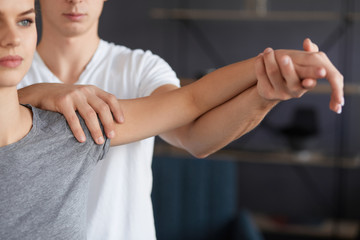 Female patient doing physical exercises with physiotherapist. Male therapist treating injured...