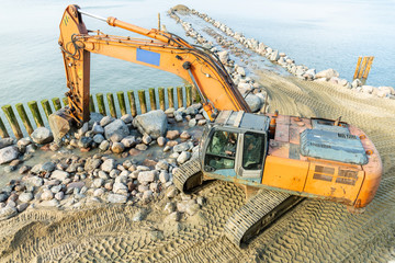 excavator on the beach, strengthening the beach and installing breakwaters
