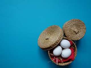 festive Easter layout of three eggs in a straw basket on a colored background