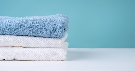 stack of clean towels on blue background - obrazy, fototapety, plakaty