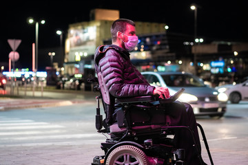 Disabled man on wheelchair wearing medical face mask for coronavirus protection.