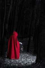 Attractive woman dressed a little red riding-hood walk in a dark forest with lantern - 329424639