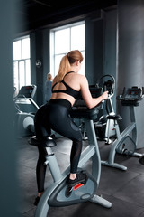 Fototapeta na wymiar Girl on exercise bike in gym