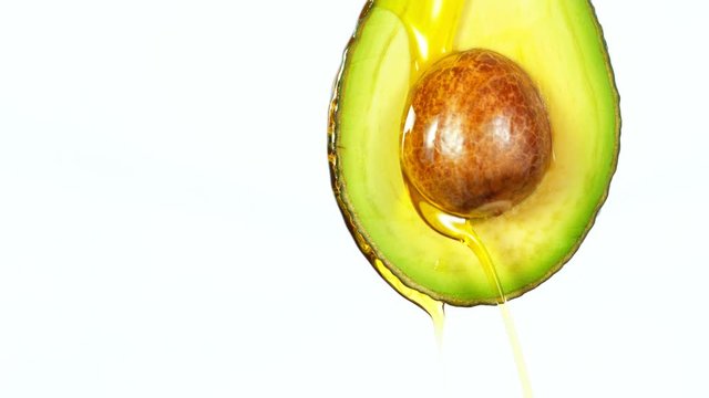 Fresh cut avocado with oil stream. Concept of healthy fruit also useful in cosmetics. Shot with high speed cinematic camera, super slow motion