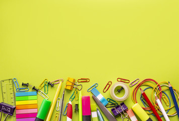 Back to school. Bright composition of school supplies on a yellow background: colored pencils, pens, markers, ruler, stickers, paper clips. Space for text at the top. Flat lay, copy space
