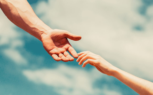 Giving a helping hand. Lending a helping hand. Hands of man and woman reaching to each other, support. Hands of man and woman on blue sky background