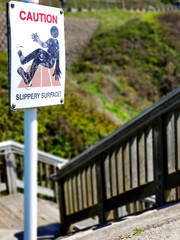 A sign warns walkers going down stairs to the beach that the surface can be slippery.