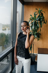 Fototapeta premium The secretary is talking on the phone near the window in the office