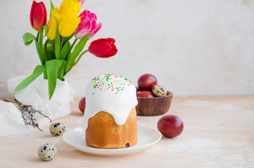 Easter composition. Easter Cake - Russian and Ukrainian Traditional Kulich with easter eggs on a light stone background. Paska Easter Bread. Selective focus. Horizontal orientation. Copy space.