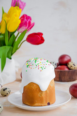 Easter composition. Easter Cake - Russian and Ukrainian Traditional Kulich with easter eggs on a light stone background. Paska Easter Bread. Selective focus. Vertical orientation. Copy space