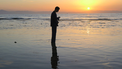 Silhouette of man practicing energy exercises at sunset by the sea