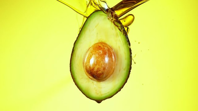 Fresh cut avocado with oil stream. Concept of healthy fruit also useful in cosmetics. Shot with high speed cinematic camera, super slow motion