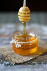 Fototapeta na wymiar Honey flows from the honey dipper. Jar of honey and a dipper for honey. Selective focus. Macro. Healthy sweets.