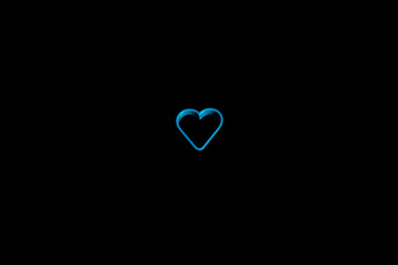 Blue plastic cookie cutter for making cookies in the shape of a heart on a black background. Culinary concept. Flat lay with copyspace.
