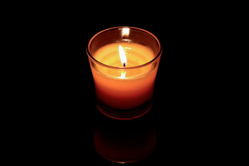 Obraz na płótnie Canvas single small candle lit in small jar on a black background