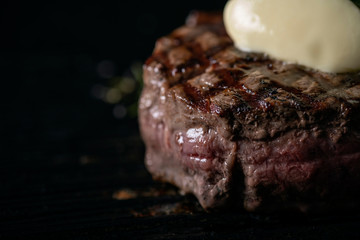 Grilled beef Tenderloin steak in a pan with butter on a dark background
