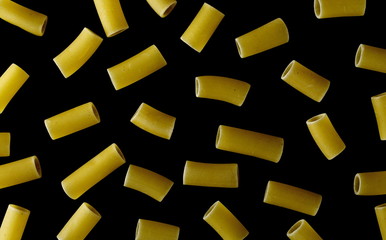 Pattern uncooked smooth short tubes shape pasta also known as tubetti lisci isolated on black background, top view and clipping path