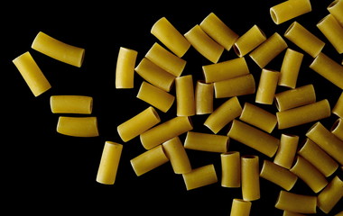 Uncooked smooth short tubes shape pasta also known as tubetti lisci isolated on black background, top view and clipping path