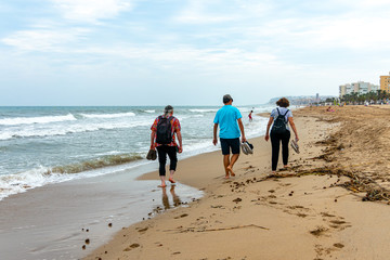 Two men and a woman walking along a beach in Alicante. Spain