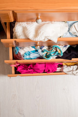 open chest drawers with sticking out randomly clothes.View from above