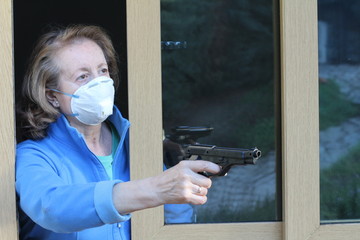 Senior woman wearing protective mask holding a weapon