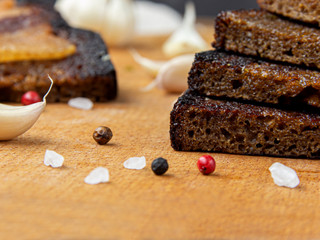 A loaf of black rye homemade bread lies on a wooden Board surrounded by garlic.