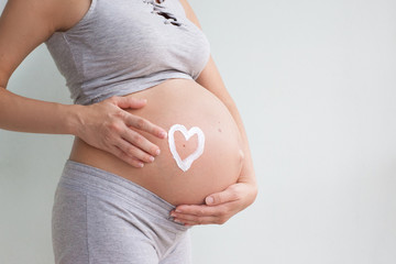 A pregnant woman applies stretch marks cream to her stomach. Stretch marks. Striae. Moisturize the...