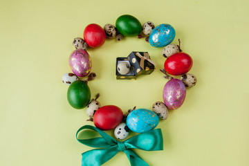 Gift and painted eggs Easter Frame in circle shape on a yellow background. Copy space, Top view